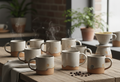 Artisanal ceramic mugs arranged on a textured wooden table, bathed in soft light.