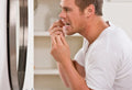 A man using dental floss in front of a bathroom mirror for oral hygiene.