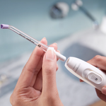 Hands attaching a replacement brush head to a white electric toothbrush handle.