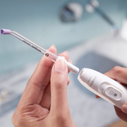 Hands attaching a replacement brush head to a white electric toothbrush handle.