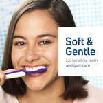 Smiling woman using a soft toothbrush for sensitive teeth and gum care.